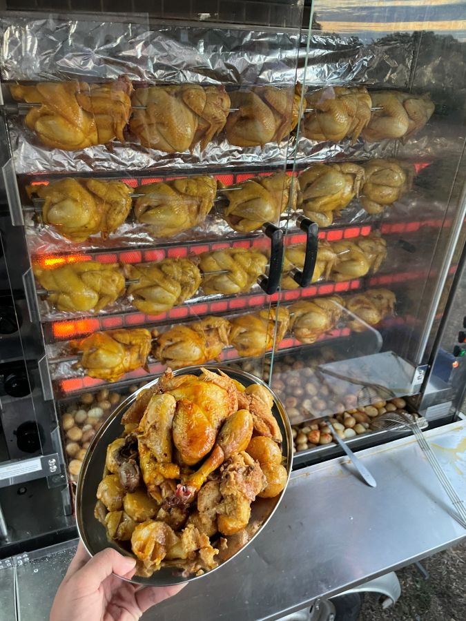 Un poulet rôti présenté devant la rôtissoire